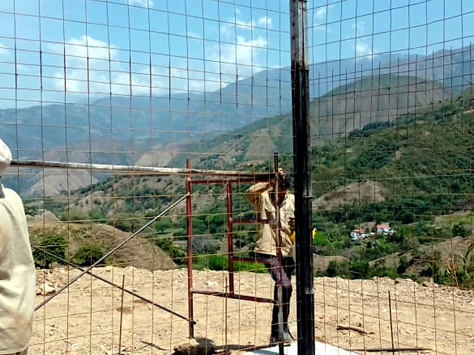 Operario sobre andamio ajustando la malla del muro