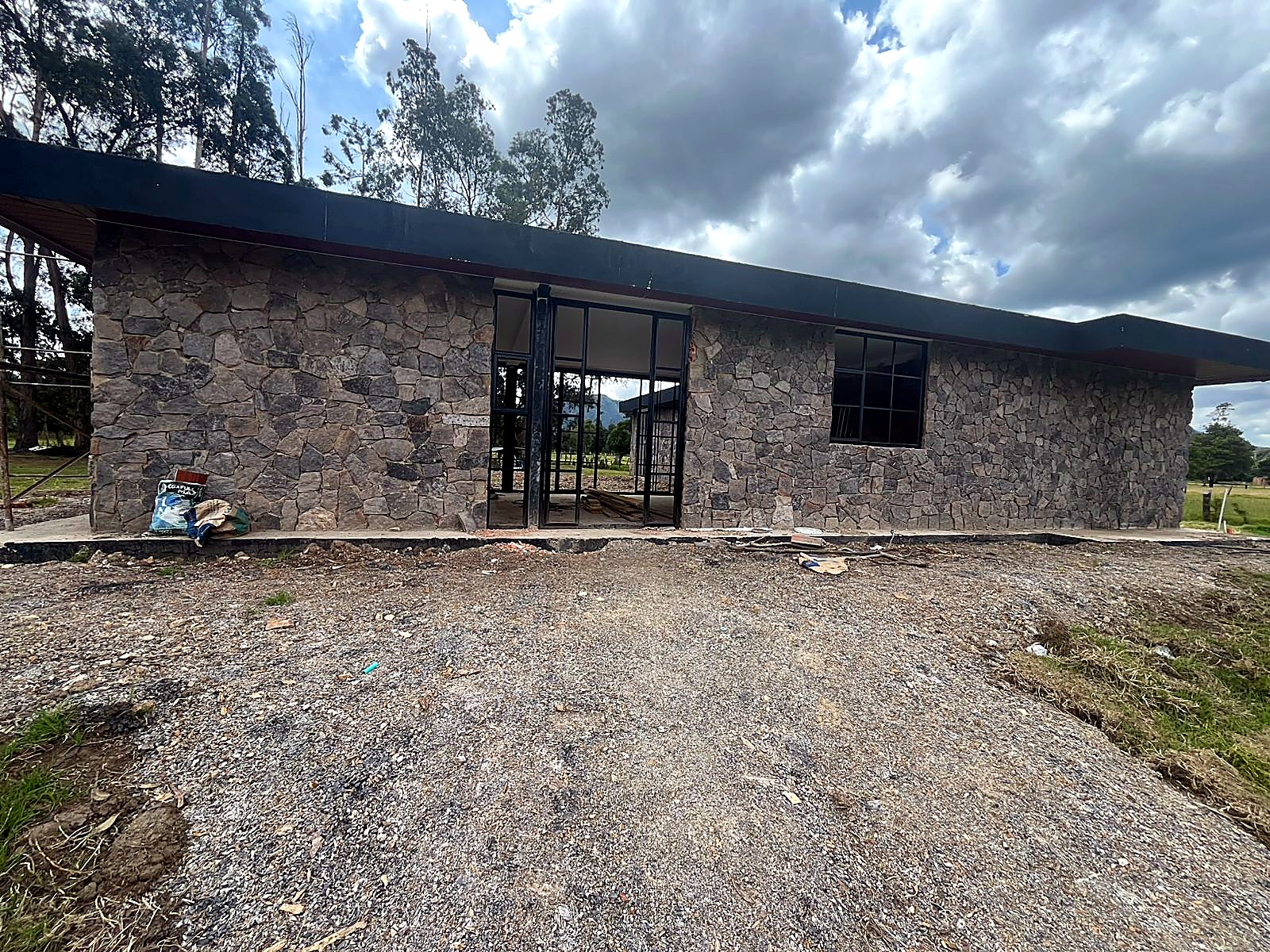 Fachada posterior en piedra con puerta ventana en carpintería negra