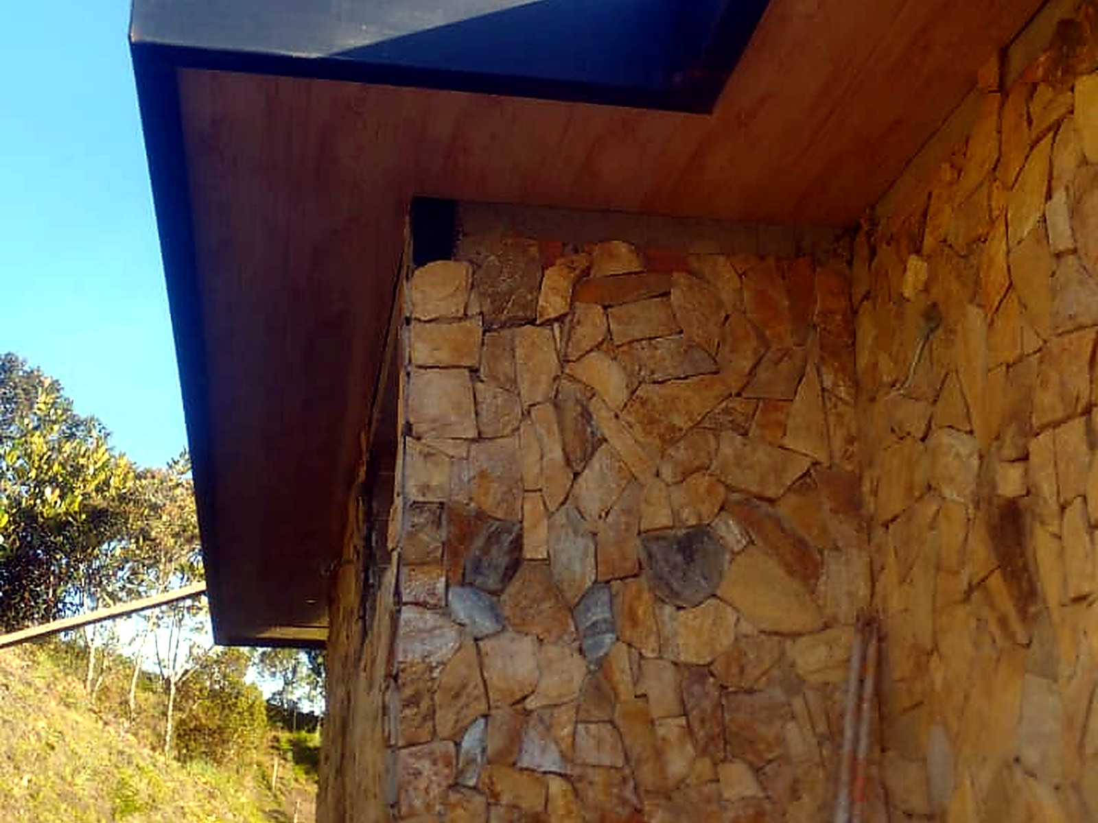 Detalle del alero en lámina negra sobre el muro en piedra