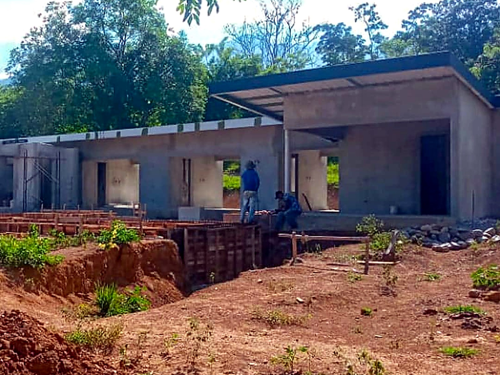 Vivienda en concreto a la vista con alero y vigas de cimentación en primer plano