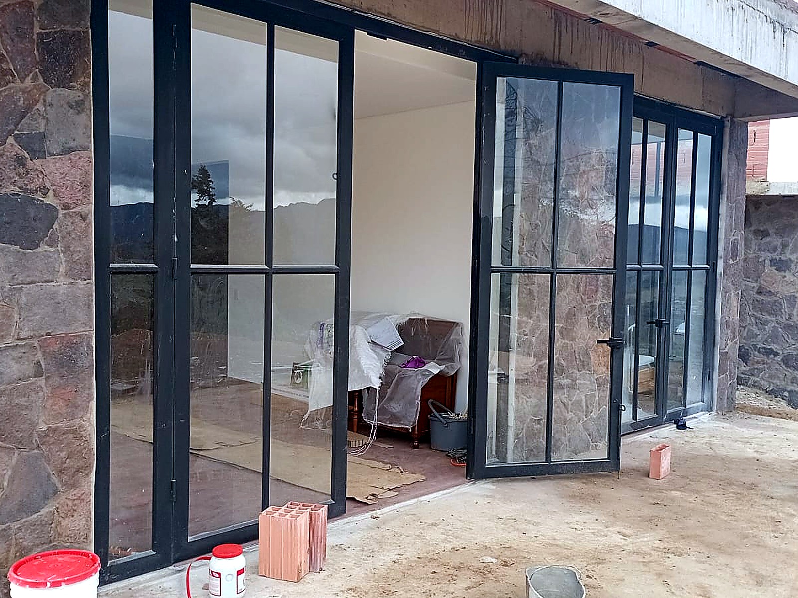Puertas abatibles en acero y vidrio entre muros en piedra