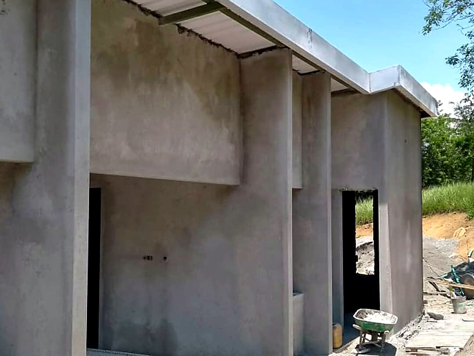 Fachada lateral en concreto con cubierta metálica y vanos hacia el corredor