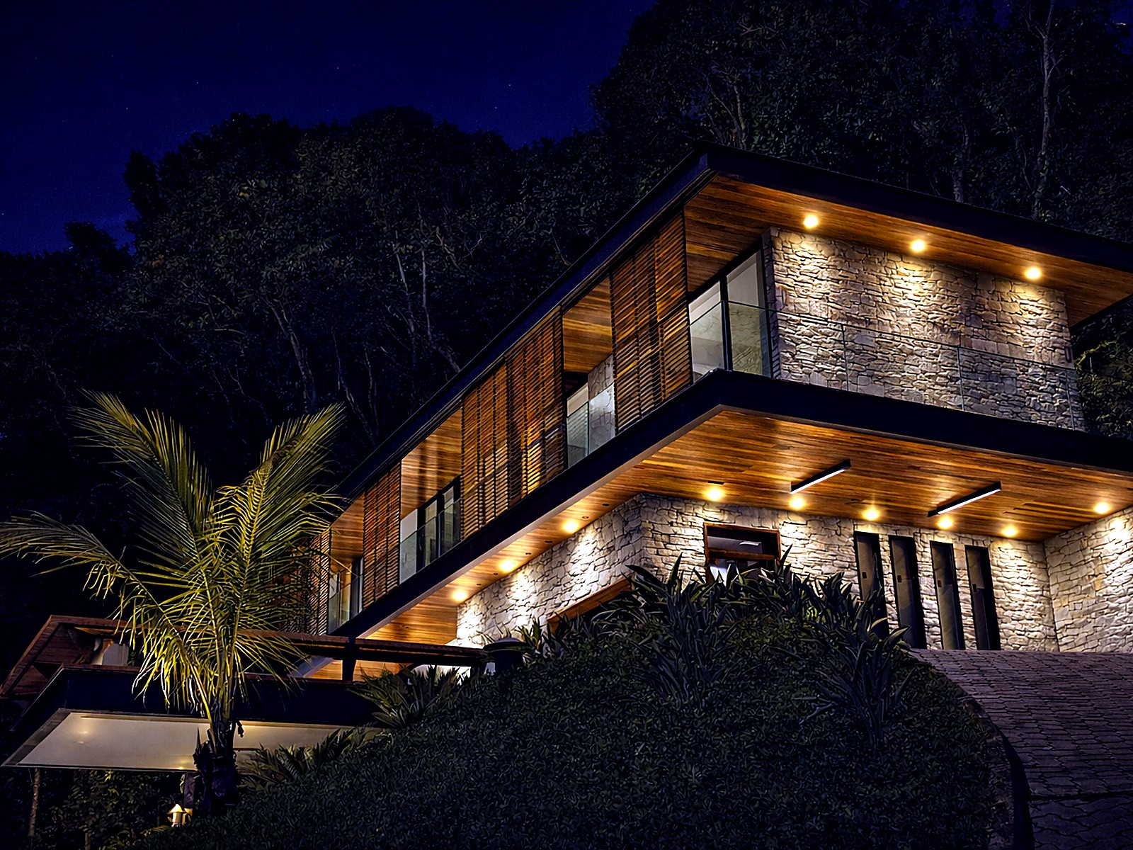 La misma casa en la noche con iluminación cálida en cielos de madera