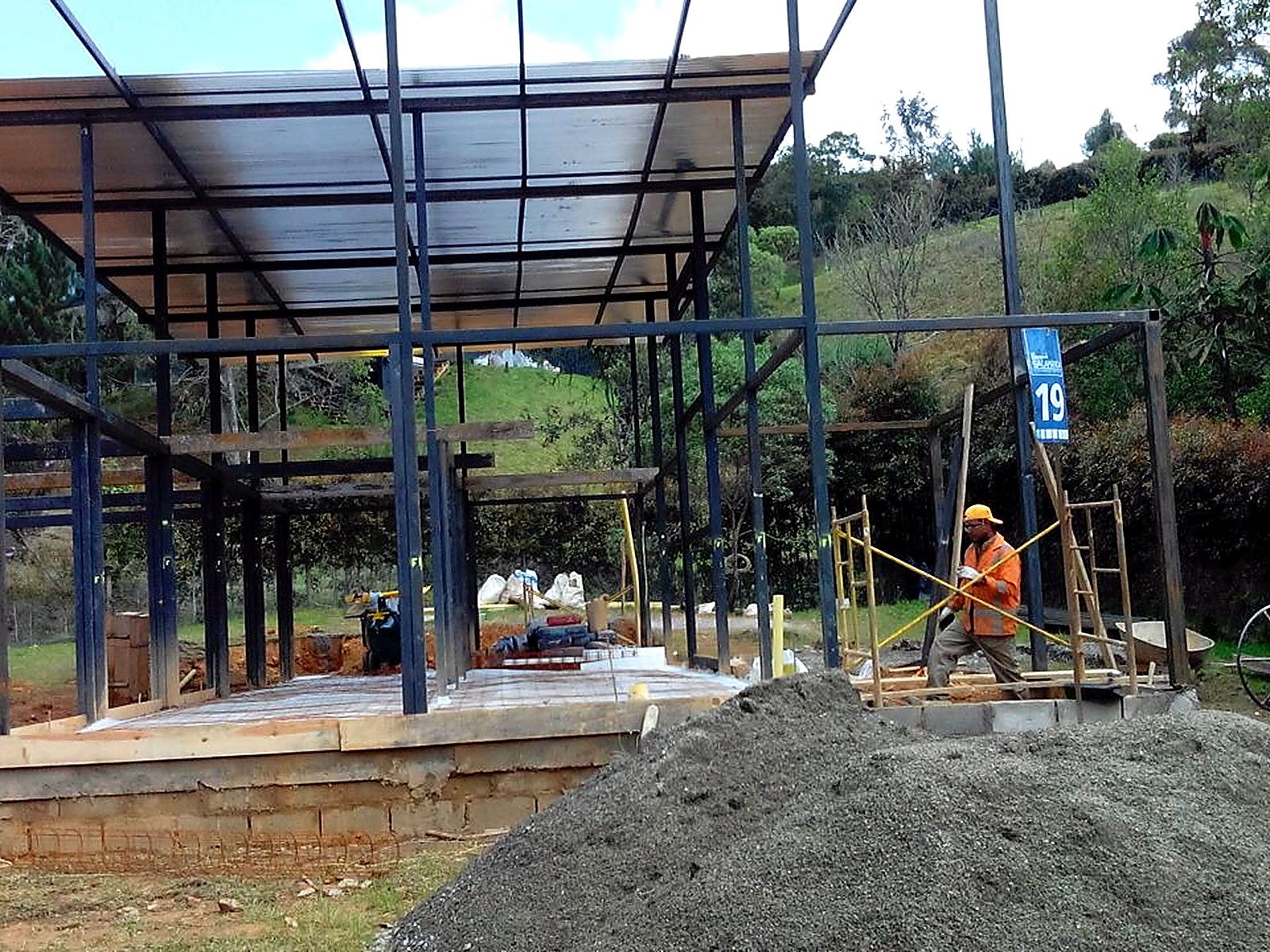 Estructura metálica de dos niveles con obrero preparando la placa
