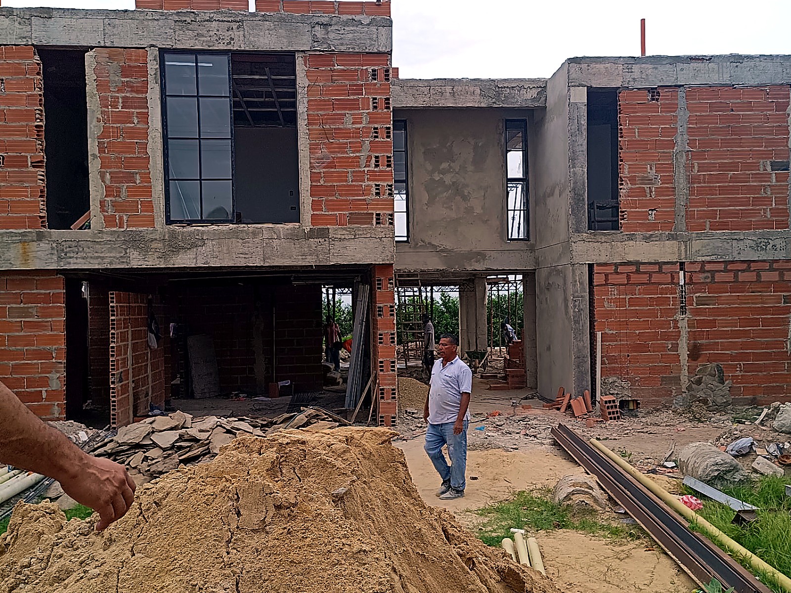 Fachada en ladrillo con ventanales metálicos cuadriculados en construcción