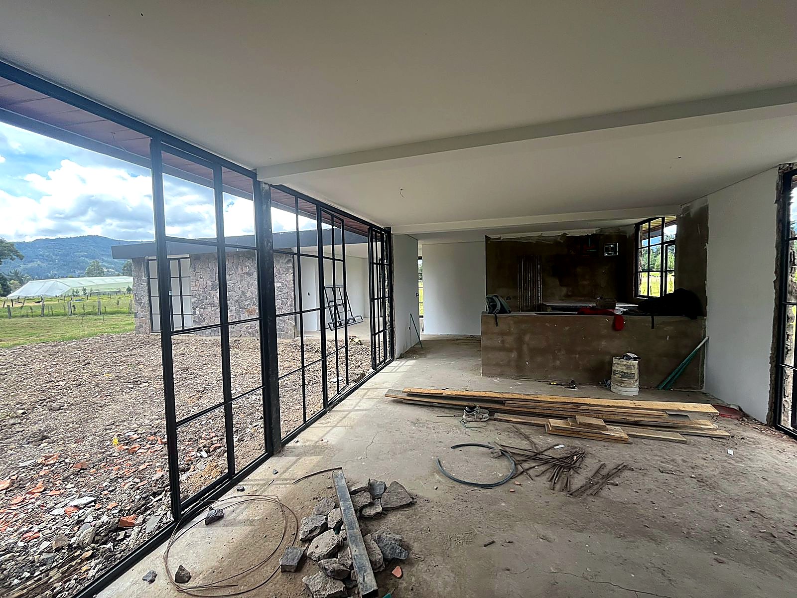 Interior con ventanal continuo hacia el potrero y mesón en obra