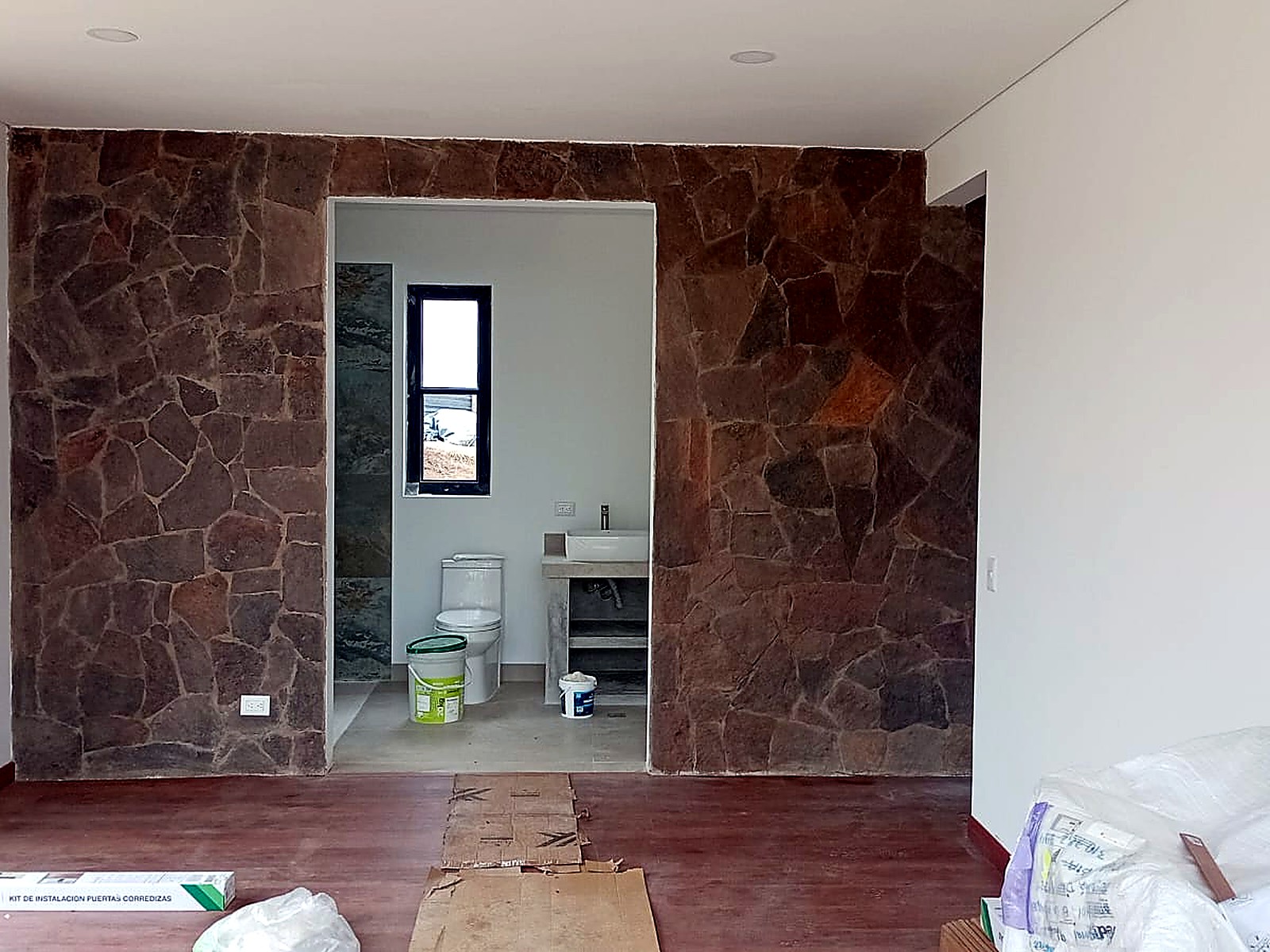 Interior con muro en piedra y acceso al baño