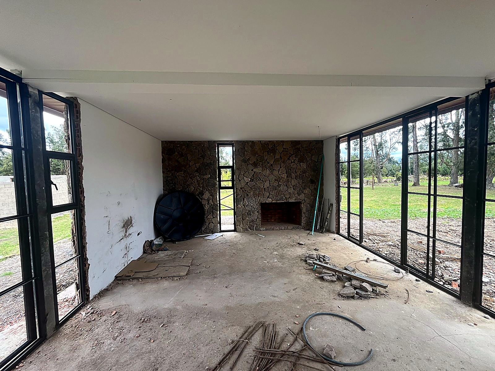 Sala con chimenea en piedra y ventanales en dos costados