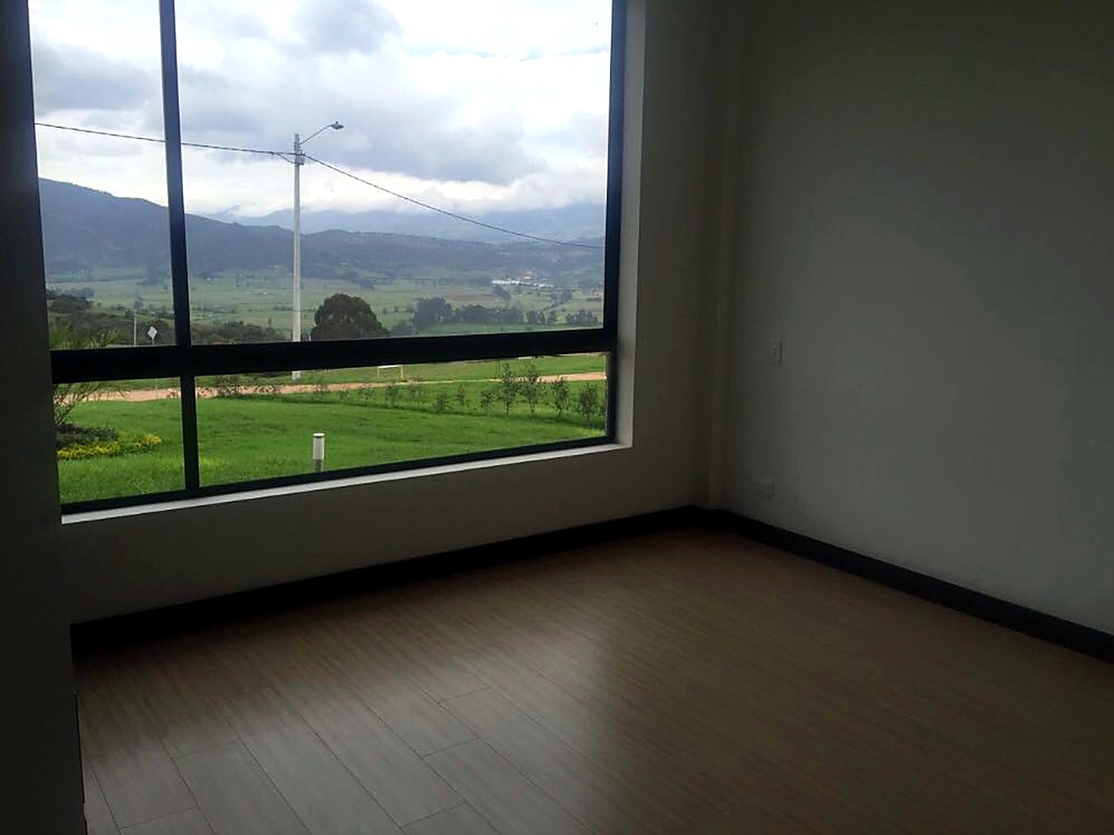 Habitación terminada con ventanal hacia el valle y piso en madera