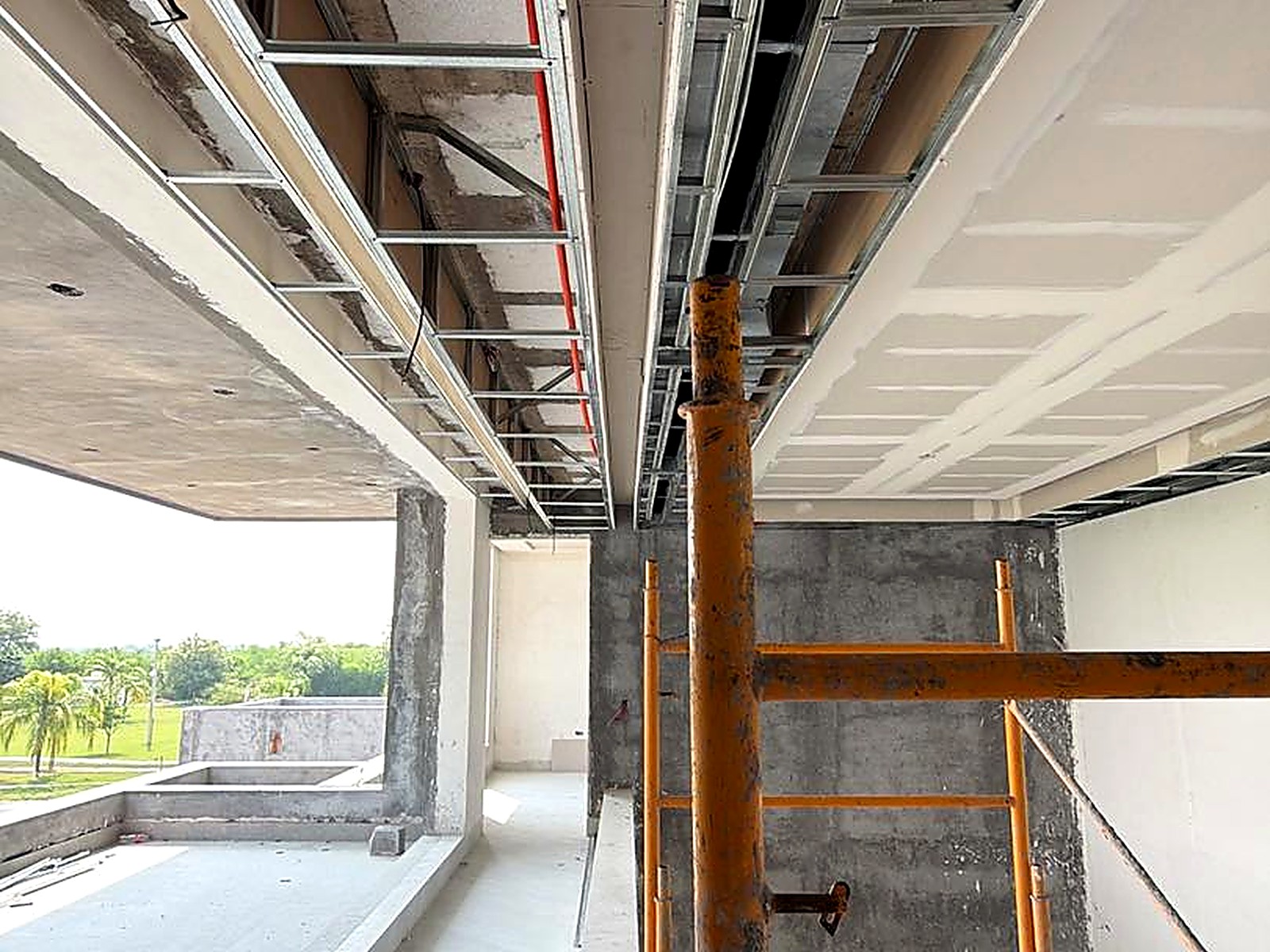 Corredor en voladizo con cielos en drywall y andamios