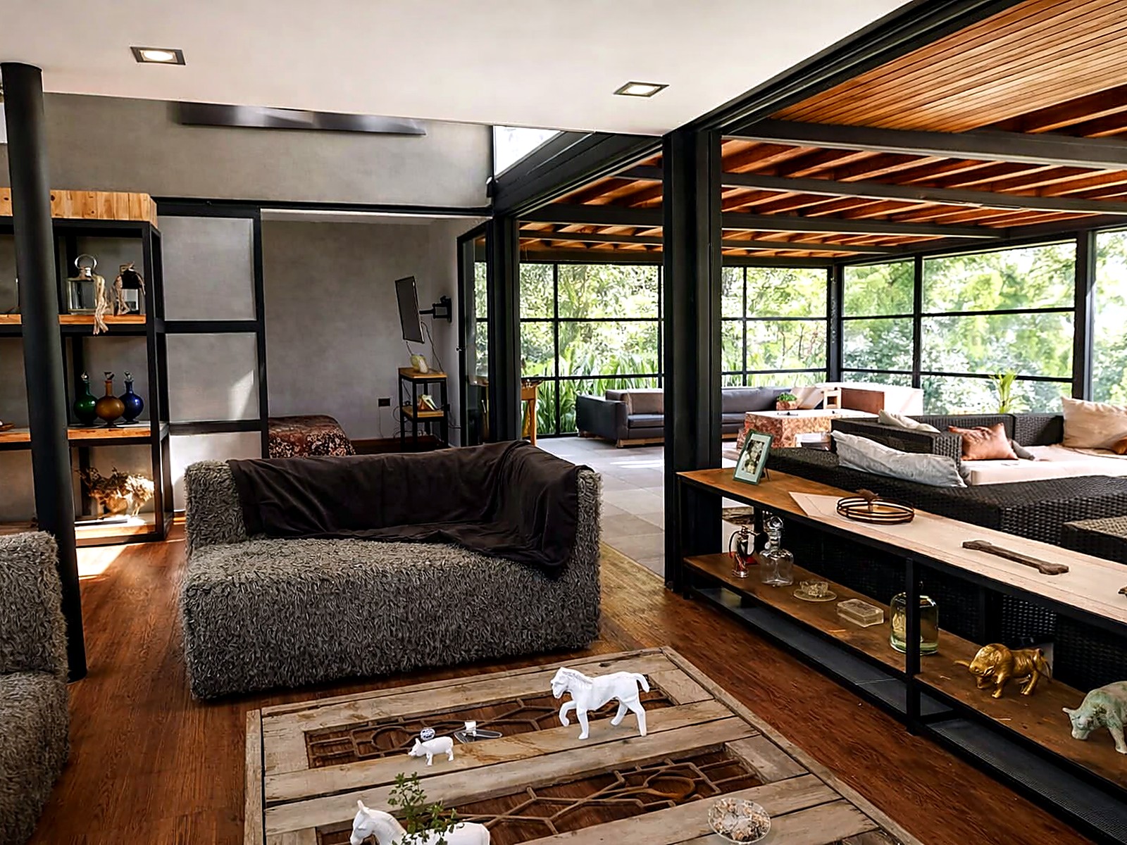 Sala con cielos en madera, columnas metálicas y ventanales al jardín