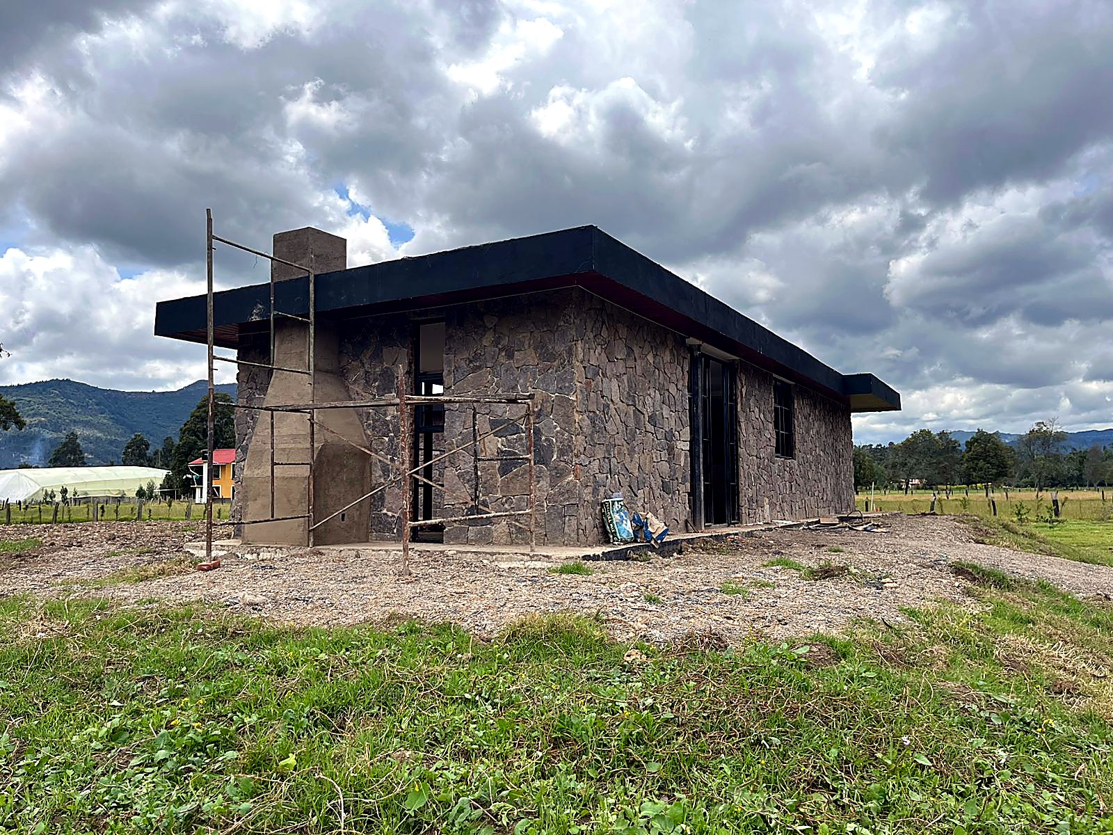 Costado de la casa en piedra con chimenea y alero negro