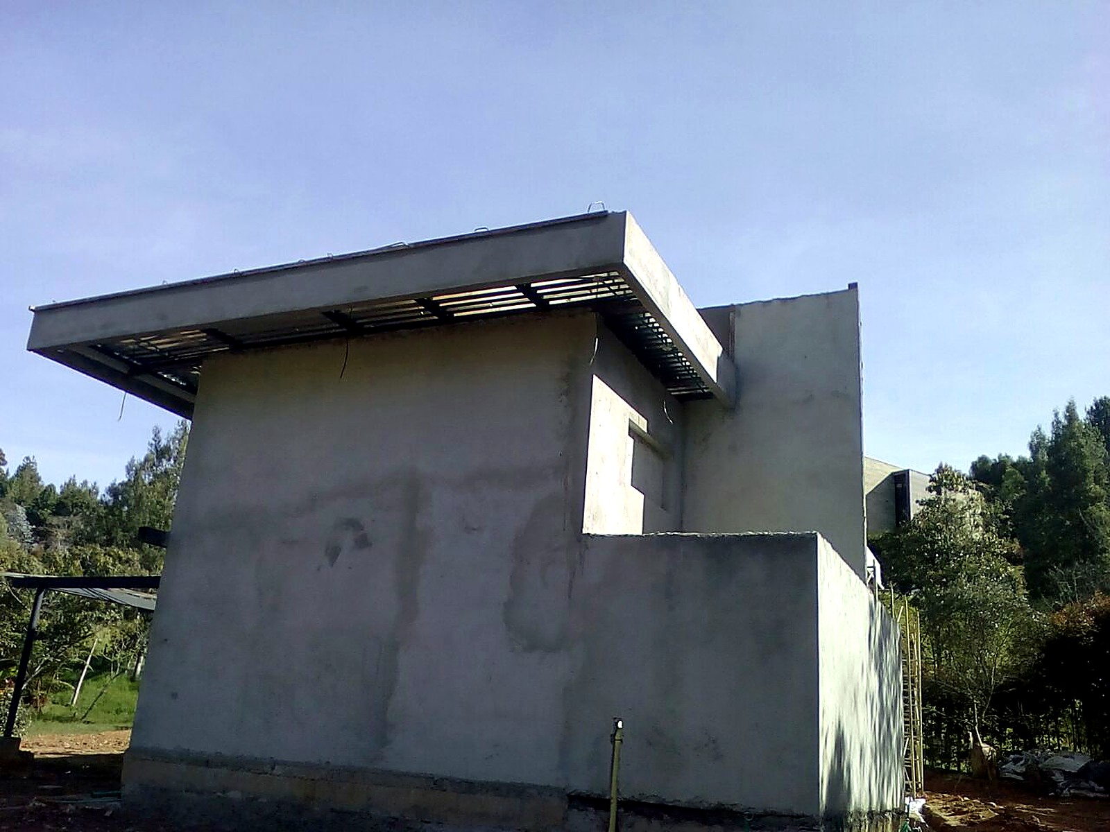 Fachada en concreto con voladizo de cubierta terminada en obra gris