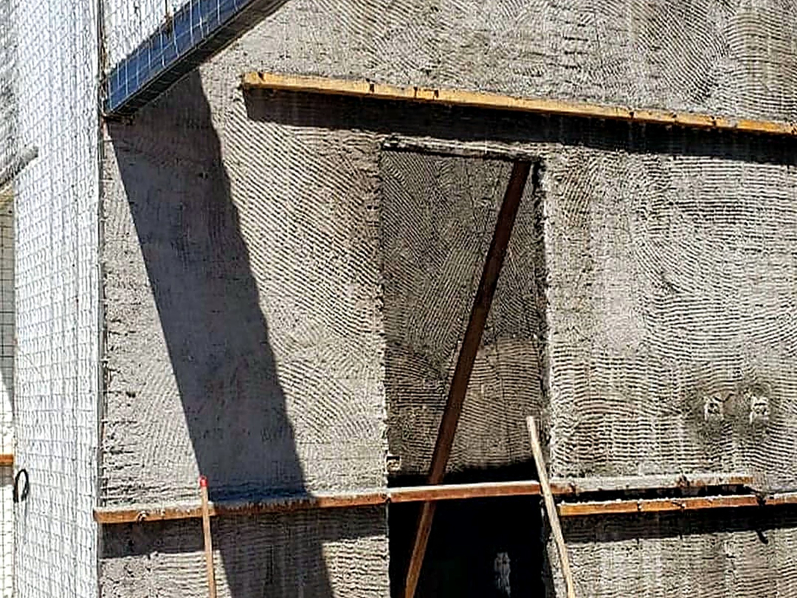 Fachada con mortero lanzado sobre panel estructural y andamios de madera