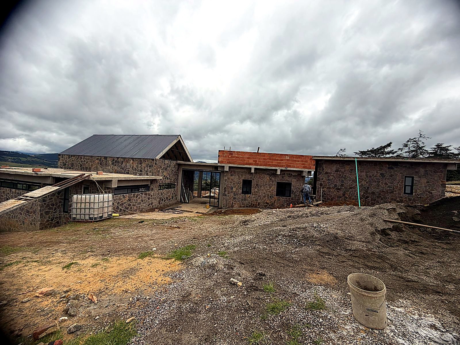 Casa en piedra con cubierta metálica a dos aguas y ventanal en el frontón