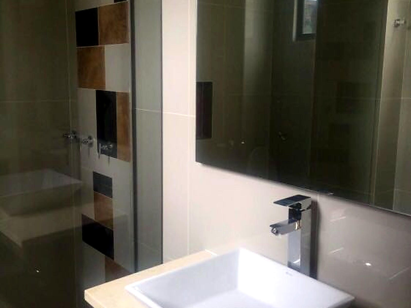 Baño con lavamanos de sobreponer, mesón en piedra y ducha en vidrio