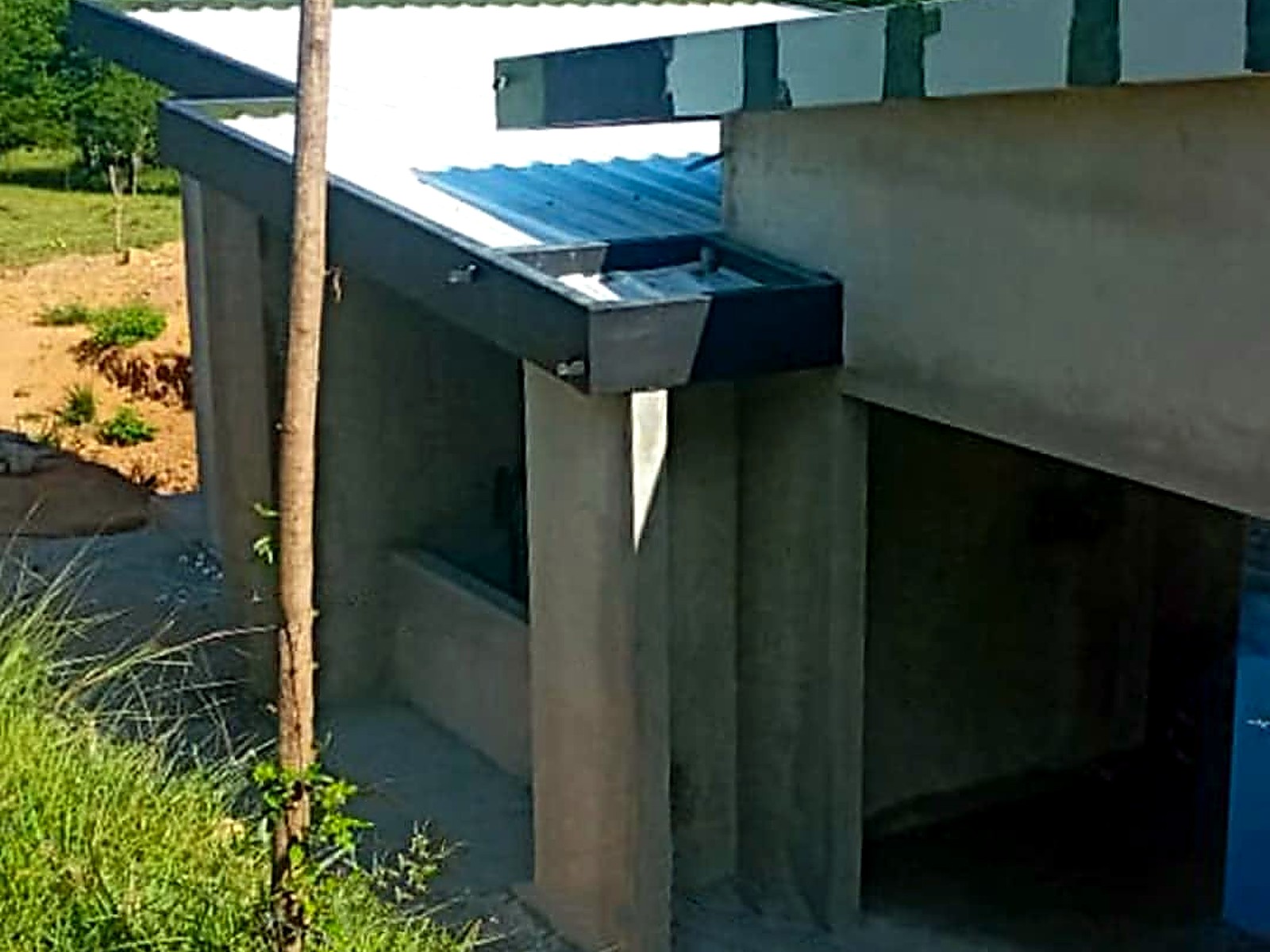 Volumen en concreto con cubierta metálica inclinada frente a las montañas
