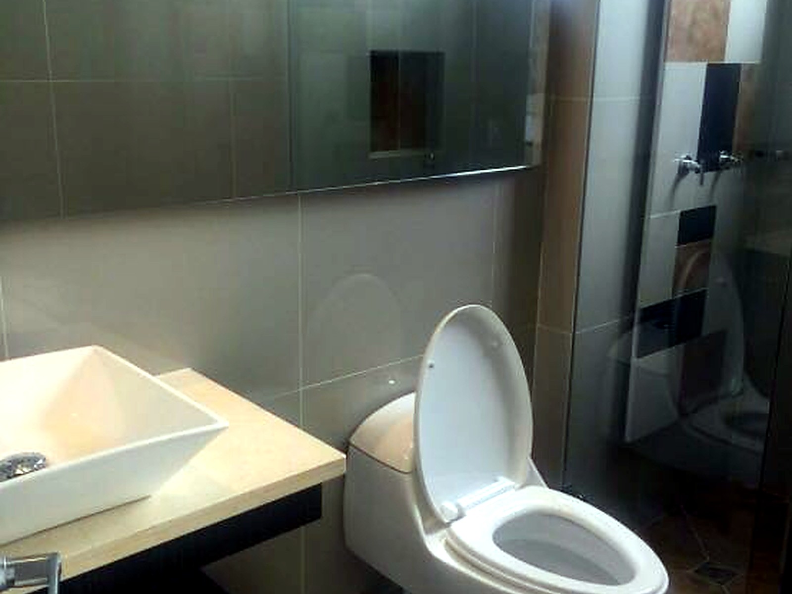 Baño terminado con enchapes claros y ducha con cenefa en mosaico