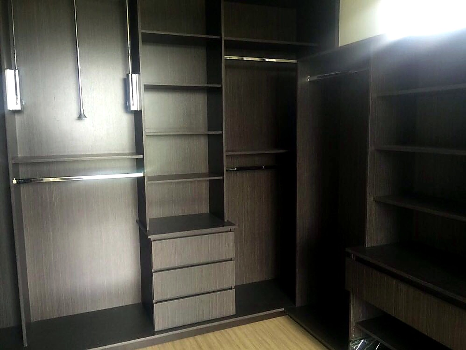 Vestier en madera oscura con entrepaños y barras iluminadas