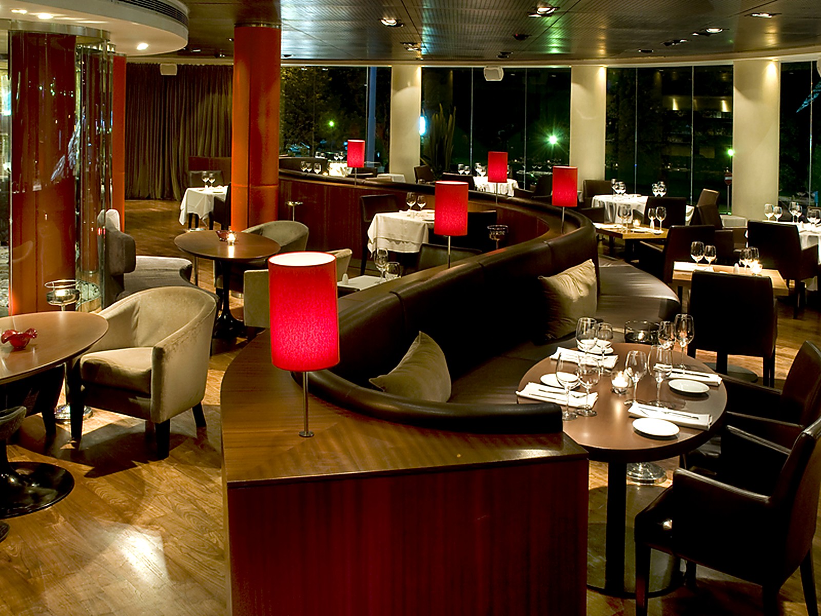 Salón lounge con poltronas, mesas redondas y columnas rojas